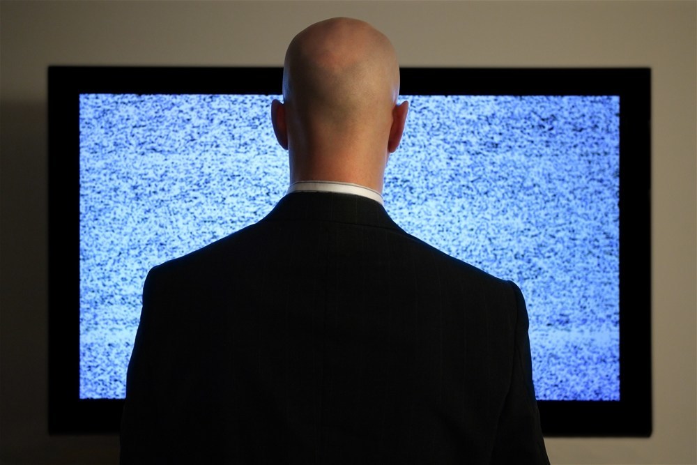 A man watching a blank or static screen of his television.