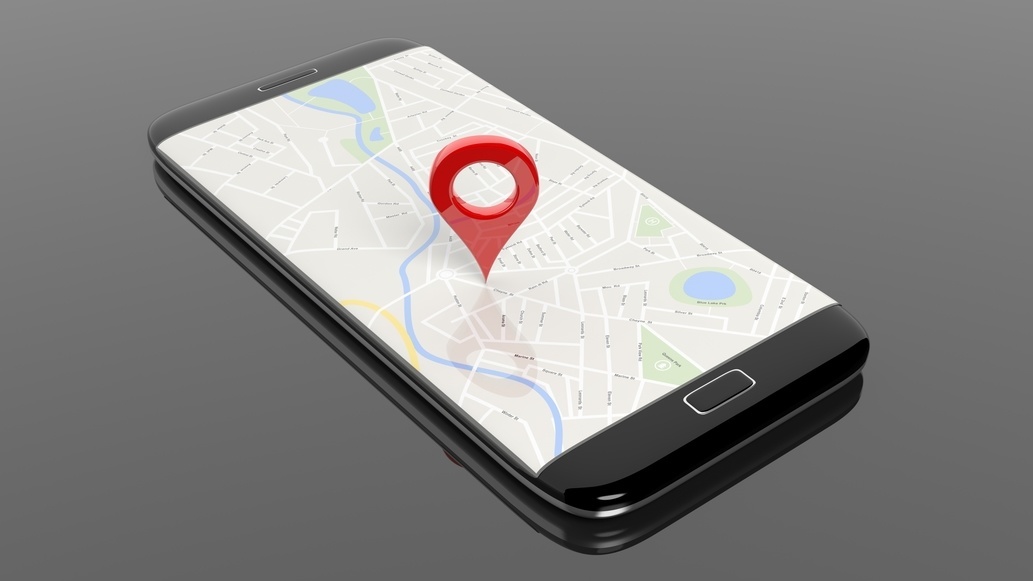 Smartphone with map and red pinpoint on screen, isolated on black background.